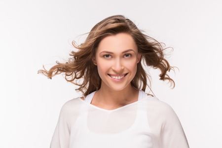 Attractive blonde lady smiling for photo camera. Woman in white fashion T-shirt with perfect skin...