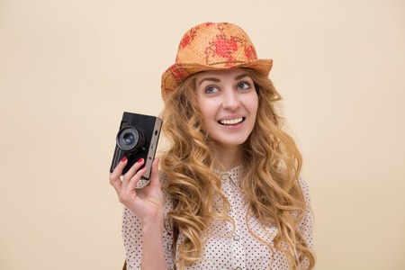 Beautiful woman with long curly red hair gloating. Girl with cool photo camera smiling.の写真素材
