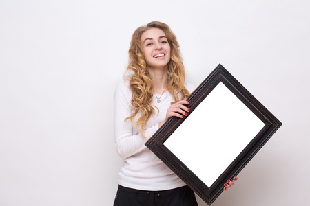 Young pretty lady holding white picture. Long-haired woman smiling isolated on white background.の写真素材