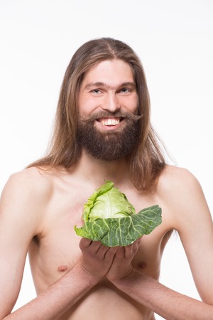 Smiling handsome vegetarian demonstrating healthy food. Naked body man carrying young cabbage.の写真素材