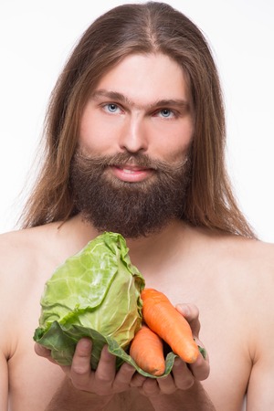 Vegetarian carrying eko products. Long-haired bearded man with moustache demonstrating cabbage and carrots.の写真素材