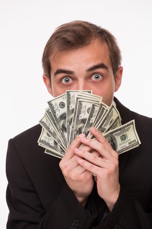 Businessman keeping much money in his hands. Scroodge in business suit looking surprised.の写真素材