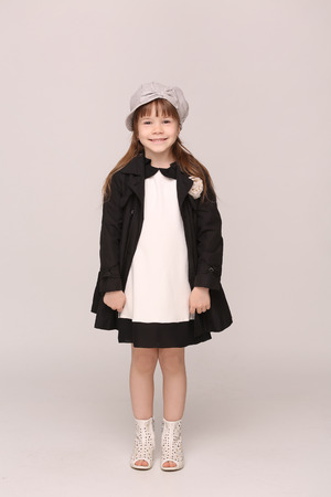 Little model posing in fashionable dress and coat. Girl in beautiful hat smiling.の写真素材