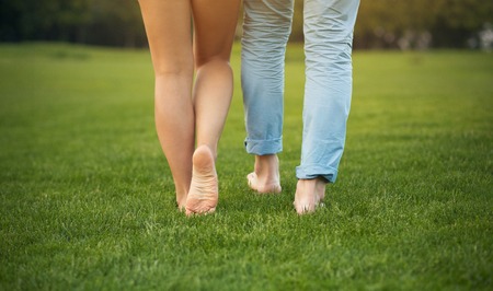 Legs of young couple on the grass. Man and woman happy walking in the park.の写真素材
