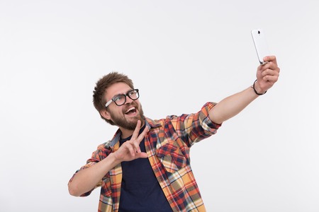 Bearded man posing with white smartphone. Happy man video communicating with his friends using...