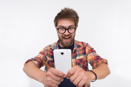 Profile of very happy bearded man with smartphone. Short-haired man in glasses looking at funny...