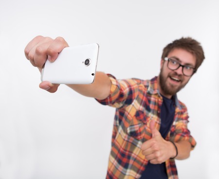 Close-up photo of back side of white smartphone. Bearded man keeping up-to-date mobile phone and showing OK sign.の写真素材