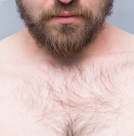 Close-up cropped image of man's face and chest isolated on grey. Srius man posing with his naked body.の写真素材