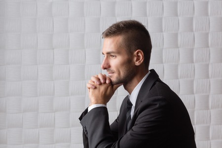 Close-up profile of smiling businessman isolated on white. Happy bearded man with short hair clasped his hands.の写真素材