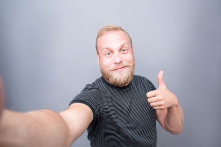 Blond bearded man making selfies. Man showing okay sign and smiling for the camera with great...