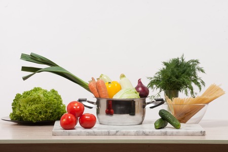 Still-life with vegetables laid in the kitchen. Multi-coloured vegetables, such as: cucumbers, tomatoes, leek, onion, carrot, cabbage etc. on the counter.の写真素材