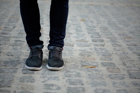 Young man's legs in black jeans and sneakers on the street. Man walking in the centre of the city.の写真素材