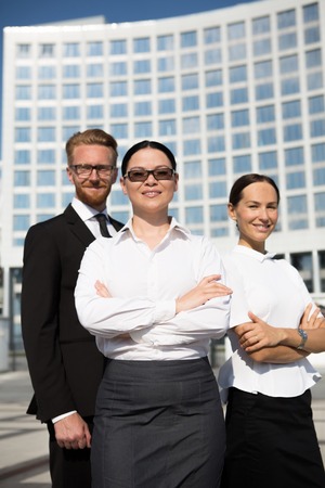 Office, business and teamwork concept. Friendly young smiling businesswoman in sunglasses with team on back with her arms folded.の写真素材