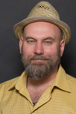Portrait of smiling bearded man in straw hat. Happy man in yellow shirt posing for photographer on...