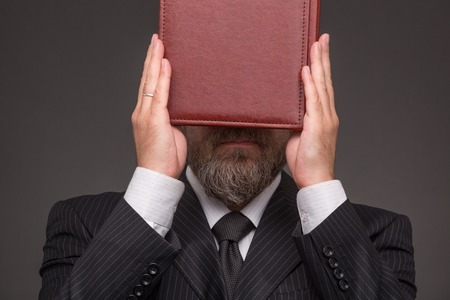 Hipster bearded businessman doesn't want to see anything. Man in black business suit hiding behind...