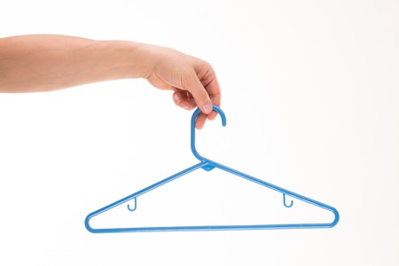 Fashion and vogue concept. Man's hand holding blue-coloured clothes hanger isolated on white background.の写真素材