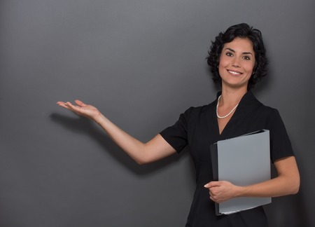 Businesslady speaking about necessary business things. Woman posing in black suit and holding documents in her hand. She is telling something.の写真素材