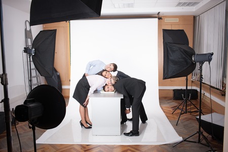 Close-up portrait of group of business people with their heads all together. People posinf in photostudio near table isolated on white.の写真素材
