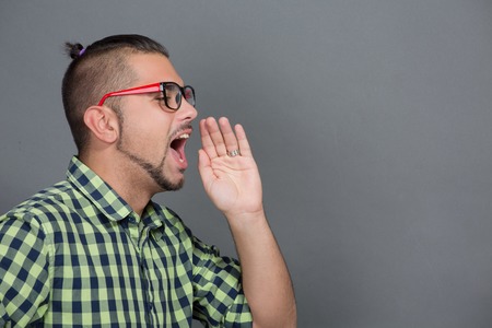 Close-up profile of fashionable hipster man shouting to someone in photo studio. Young freelancer dreaming about his career.の写真素材