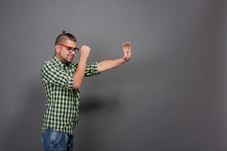 Fashionable hipster man using an imaginative tube in studio. Young man in shirt and jeans trying to...