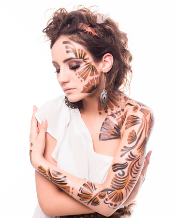 Portrait of beautiful lady with bodyart isolated on white background. Lady with closed eyes hugging herself.の写真素材