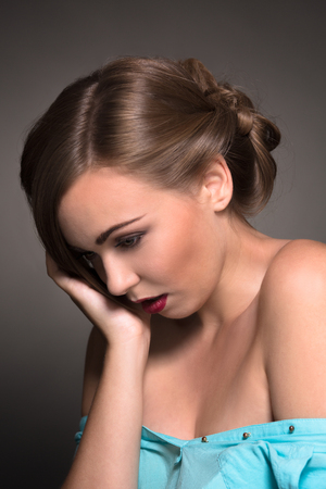 Sad beautiful woman having depression and stress. Model posing for photographer in blue dress isolated on white background.の写真素材