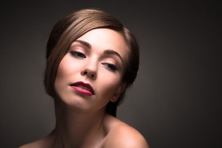 Portrait of elegant woman having depression and stress isolated on dark background. Beautiful lady demonstrating her perfect make-up.の写真素材