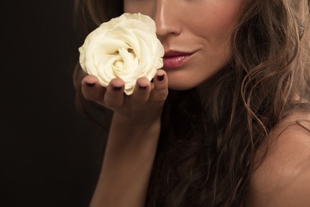 Beautiful woman with elegant white rose isolated on black background. Lady's kisses are compared with rose petals.の写真素材