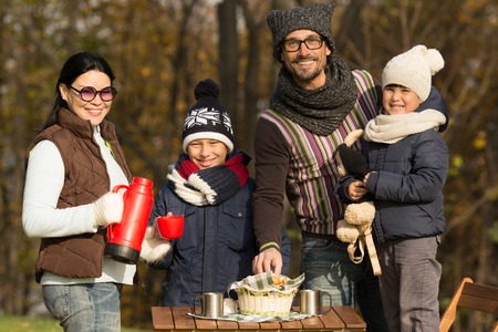 Family and picnic concepts. Happy young parents spending time with their children in the park. Young people smiling to the camera on a picnic.の写真素材