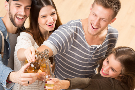 Top view shot of happy friends with alcohol cocktails making cheers. Two men and two women spending their free time in good company.の写真素材