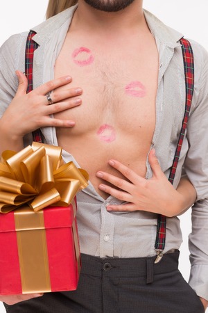 Close-up portrait of man's body with many kisses. Man holding a present while his girl-friend touching his body.の写真素材