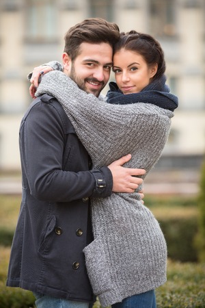 Portrait of happy smiling couple hugging in the autumn park. Man and woman looking at the camera.