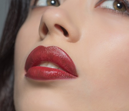Close-up portrait of fashion or vogue lady posing for fashion magazine or catalogue and representing her beautiful dark red lips in studio.の写真素材