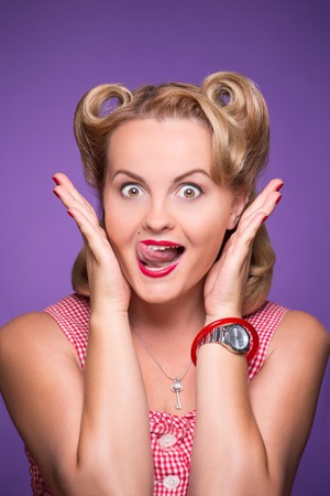 Attractive blond woman smiling for the camera and showing her tongue. Fashionable girl with red lips...