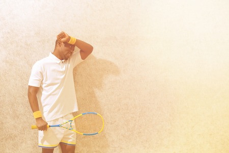 Squash player holding racket and touching his forehead after competition on squash court. Black man....