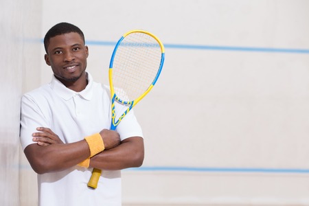 Male squash player posing for photographer isolated against white background. Happy smiling black...