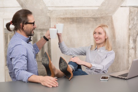 Happy business corporate partners relaxing and resting in office after hard working day. Business people drinking cups of coffee.の写真素材