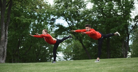 Picture of sport man and woman training in green park making stretching exercises. Couple doing sport with nature.の写真素材