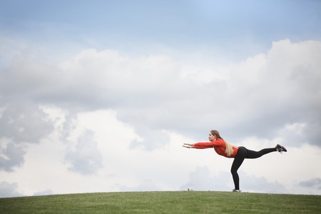 Picture of sport woman training in green park or forest. Young beautiful lady in red jacket training with nature during sunset or sunrise.の写真素材