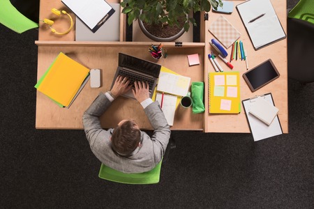 Top view of young businessman sitting in front of laptop computer and working over business projects in office.の写真素材