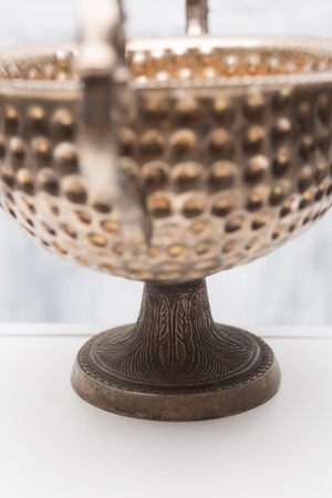 Closeup picture of ancient metalic bowl represented on table isolated on white wooden background. Bowl used franrances and perfumes.の写真素材