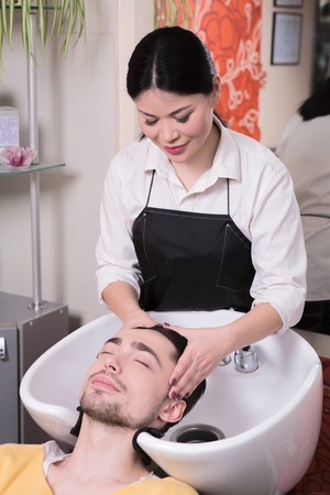 Picture of hairdresser washing handsome man's hair in beauty saloon. Handsome man in hairdressing saloon.の写真素材