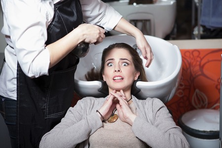 Portrair of frightened beautiful lady while having her hair wash in hairdressing saloon. Pretty lady looking at camera.の写真素材