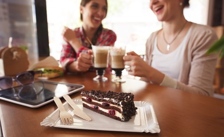 Ladies having round or cheers with cups of latte. Toned image of best friends meetig or date in cafe or restaurant.の写真素材