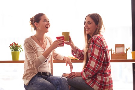 Toned picture of pretty ladies having round or cheers in cafe or restaurant. Best friends or colleagues drinking delicious cocktails or coffee.の写真素材
