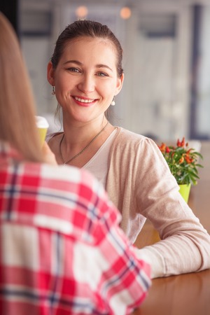 Toned picture of beautiful lady looking at camera while spending her free time with best friends in cafe or restaurant.の写真素材