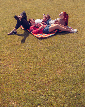 Picture of best friends resting and relaxing on rug while spending free time in park.の写真素材