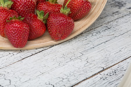 strawberries on wooden plate on white wooden table.の写真素材