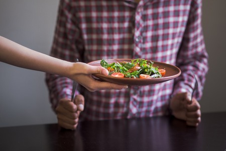 Picture of vegan dish is being served in vegan restaurant or cafe. Man sitting at table and waiting for his order.の写真素材