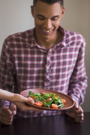 Handsome man sitting at table and waiting for his order. Picture of vegan dish is being served in vegan restaurant or cafe.の写真素材